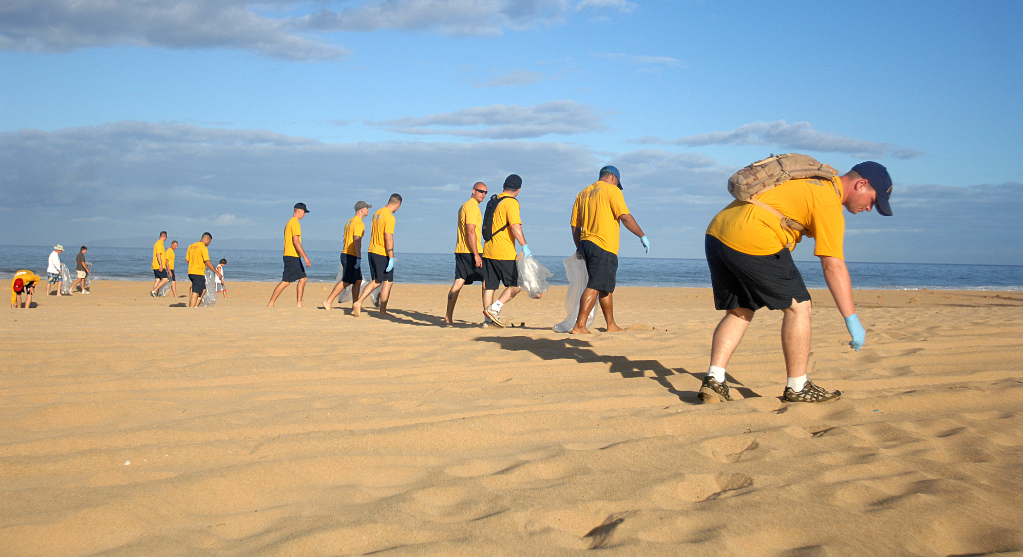 people picking up trash on the beach